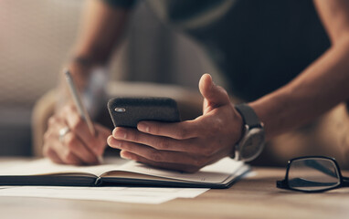 The smart app that saves you time and money. an unrecognisable man using a smartphone while going through paperwork at home.