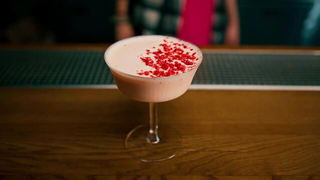 A close-up of a bar guest holding a ready-made tasty bilberry club alcoholic cocktail in his hand 
