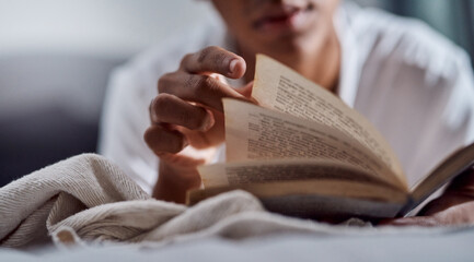 It might be time to turn a new page. a young man reading a book and relaxing on his bed at home.