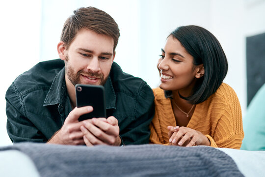 Quarantine, a time for growing your connection. a young couple using a smartphone together on their bed at home.