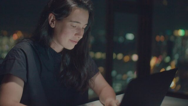 Medium shot of woman writer wearing ring working and typing poetry at night