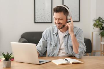 Man in headphones studying on laptop at home. Online translation course