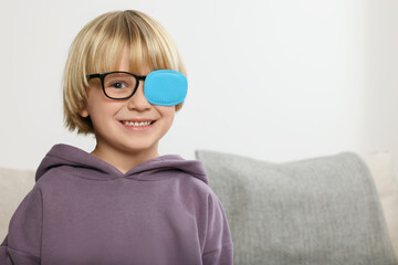 Happy boy with nozzle on glasses for treatment of strabismus in room. Space for text