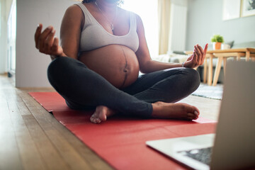 Young pregnant latina woman meditating at home wihle using a laptop