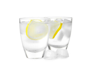 Shot glasses of vodka with lemon slices and ice on white background