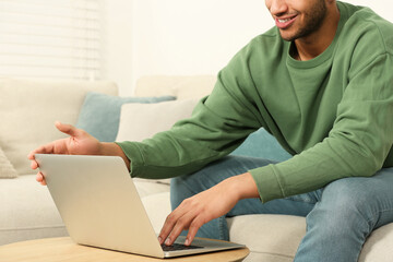 African American man working on laptop at table indoors, closeup