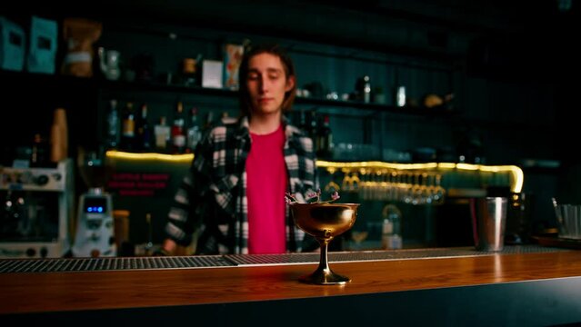 the bartender gives the customer a delicious freshly prepared raspberry milk punch cocktail from the bar counter