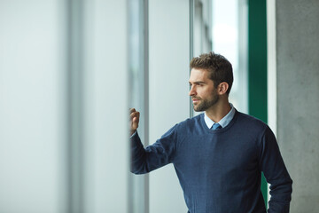 Fototapeta premium There are so many things I wish to achieve. a handsome young businessman standing alone and looking contemplative.