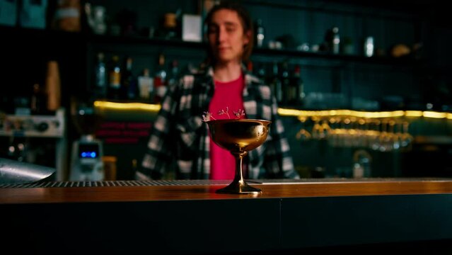 the bartender gives the customer a delicious freshly prepared raspberry milk punch cocktail from the bar counter