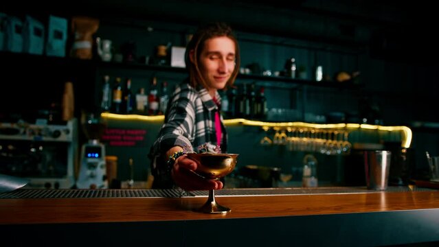 the bartender gives the customer a delicious freshly prepared raspberry milk punch cocktail from the bar counter
