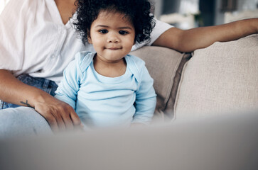 Mmm, this looks interesting. an unrecognizable woman using a laptop with her daughter on the sofa at home.