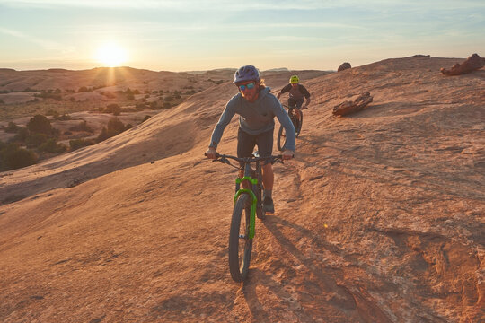 Keep Calm And Ride On. Full Length Shot Of Two Young Male Athletes Mountain Biking In The Wilderness.