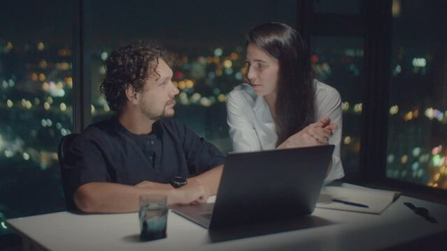 Medium shot of European family talking about work behind laptop, illuminated by the screen