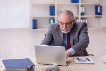 Old male employee working in the office