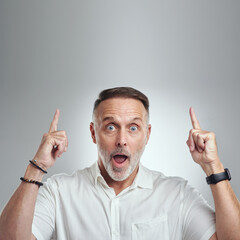 This totally blows my mind. Studio portrait of a mature man pointing to copyspace against a grey...