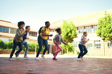 Race you back to class. Full length shot of a diverse group of children running outside during...