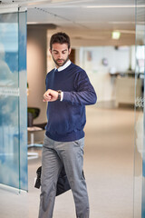 Punctuality is a sign of professionalism. a young businessman checking the time on his watch while carrying a bag.