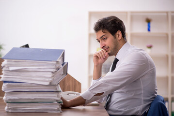 Naklejka premium Young male employee and too much work in the office