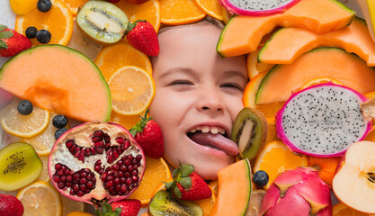 Kid tasting fruit. Funny licking fruit. Top view of funny kids face with different fruits. Summer fruits. Kids face with mix of fruits. Assorted fruits.