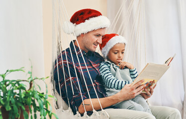 Book some time with those special to you. a young man reading a book with his adorable son at Christmas.