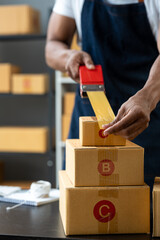 Employee or businessman holding a tape dispenser to seal parcels for delivery to customers online. ecommerce startup business ideas.