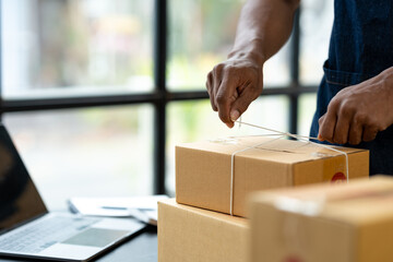 Office workers or self-employed business people use a string to tie parcel boxes for delivery to customers online. ecommerce startup business ideas.