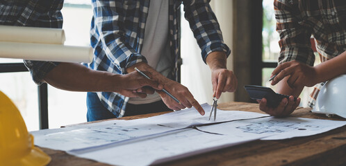 Meeting of plans and calculations on house plan drawings of engineers, architects on blue print with equipment discussing at desk. Teamwork and management concept. Construction