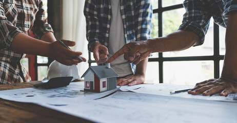 Team of engineers, architects meeting plans on blue print house plan drawing sheet with equipment to plan, discuss, set up projects together at the desk Teamwork and management concept.