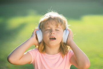 Singing children. Child with listening to music using headphones amazed with open mouth. Funny kids face.