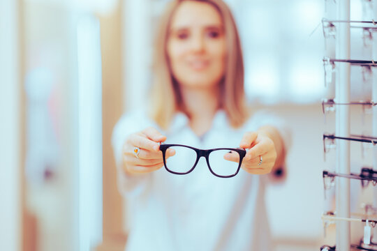 Eye Doctor Giving A Pair Of Glasses To A Myopic Patient. Optometrist Having Over Frames To Try On In A Clinic
