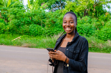 pretty young african woman smiling and using her mobile phone outdoor