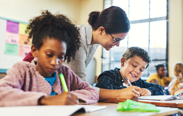 Do you need a little help. an attractive young teacher helping a student in her classroom during a lesson.
