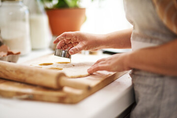 My cookies are always a hit. an unrecognizable woman cutting out cookies in her kitchen.
