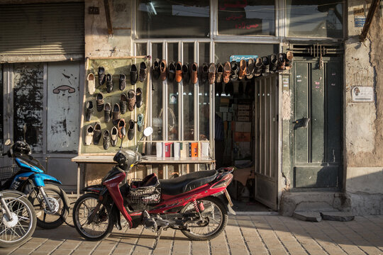 ISFAHAN, IRAN - AUGUST 20, 2018: Motorcycles standing in front og a shoemaker shop, with shoes hand in front. The Isfahan bazar is one of the symbols of the city