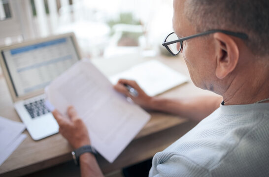 Always read the fine print. a mature man reading over financial documents while working.