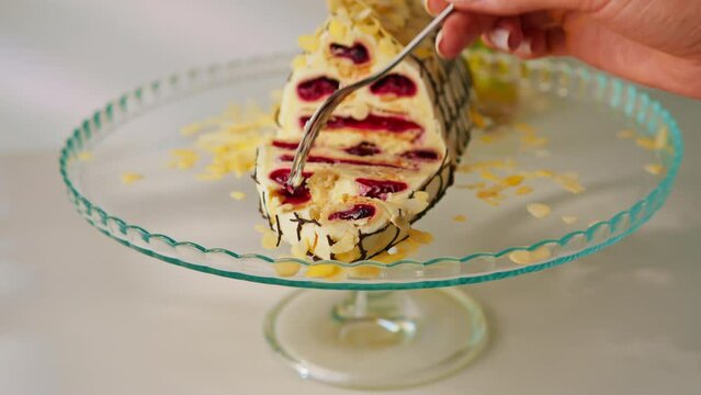 a delicious cherry cake or a monastery hut decorated with almond shavings on a stand take a piece of cake with a fork