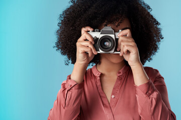 Living life one click at a time. Studio shot of a young woman using a camera against a blue background.