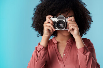 Living life one click at a time. Studio shot of a young woman using a camera against a blue...