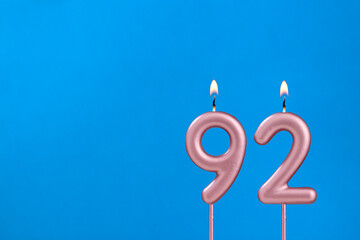 Number 92 - Burning anniversary candle on blue foamy background