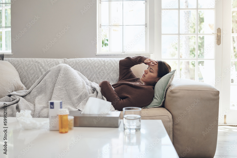 Wall mural my temperature hasnt gone down. a young woman lying on a sofa while feeling sick at home.