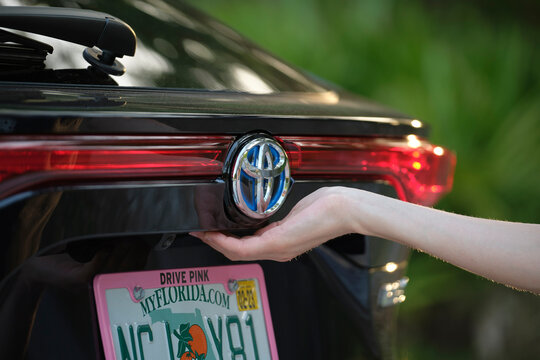 Closeup of driver hand opening car trunk lid. Tampa, USA - June 14, 2022.