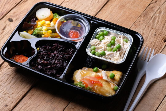 healthy food bento with black rice, dori fish fillet, vegetable soup, shredded chicken, and fruit jelly. For diet weight loss program. healthy lunch menu in a plastic container. catering menu diet. 