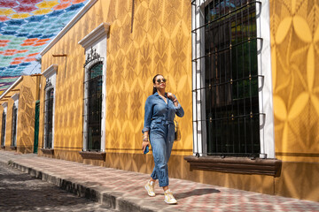 Una joven está caminando por una calle del casco histórico de Etzatlán y tiene el Cielo Tejido más grande del mundo. - obrazy, fototapety, plakaty