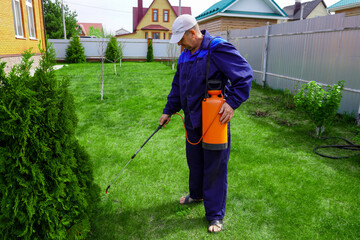 A man works in the garden, spraying weeds from a sprayer.