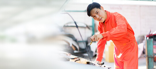 Senior Asian man checking or measuring a vehicle oil engine or engine lubricant level by using oil stick indicator. Senior professional repairman inspecting an oil engine in an old car.