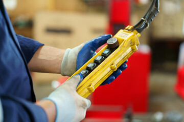 Factory worker - technician controlling a heavy crane in factory close up at his hands holing a crane controller.