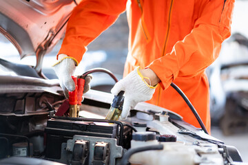Professional roadside technician support using an emergency jump start cable to connect a battery...