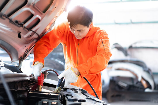 Professional roadside technician support using an emergency jump start cable to connect a battery from other car to the one which out of battery. 