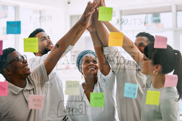 Building up our team spirit. a group of young businesspeople giving each other a high five in an...