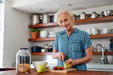 Get your fill of wellness with a healthy breakfast. a mature woman preparing a healthy breakfast in the kitchen at home. - Powered by Adobe